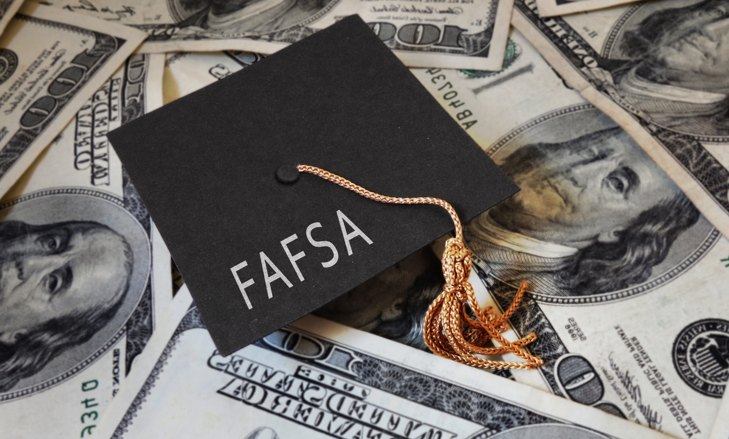 FAFSA (Free Application for Federal Student Aid) text on graduation cap and mone