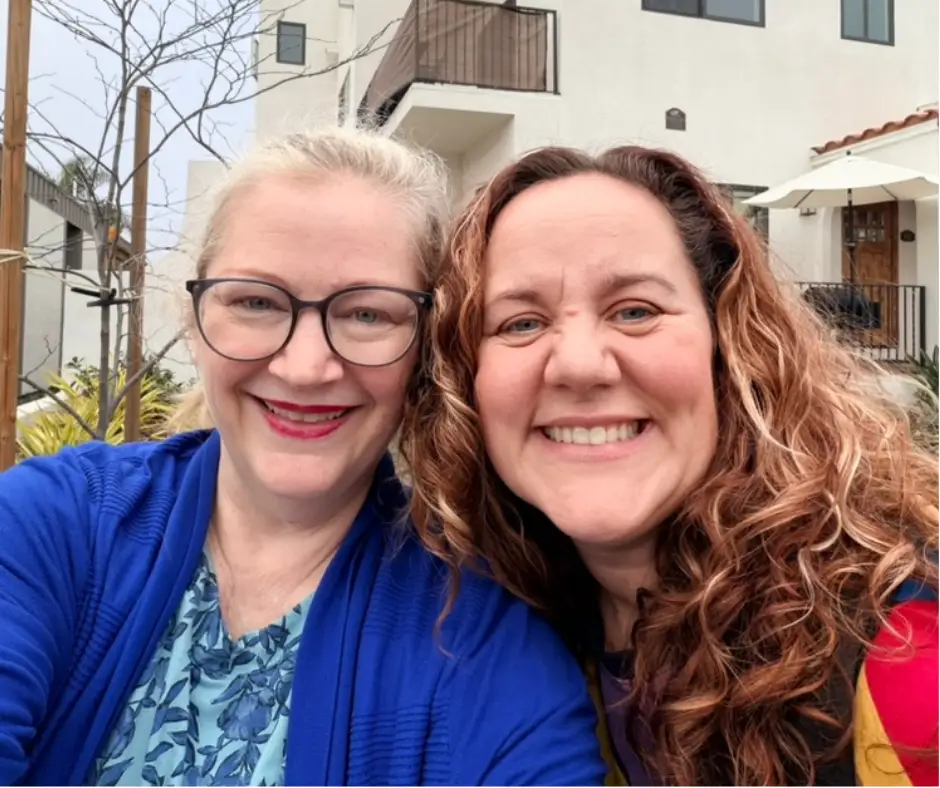 Two women smile together with an Airbnb in the background