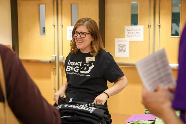 Sarah Hall, an Empire State Service Corps coordinator at SUNY Binghamton, a white woman with shoulder-length brown hair, wearing glasses and a black Impact Bing T-shirt.