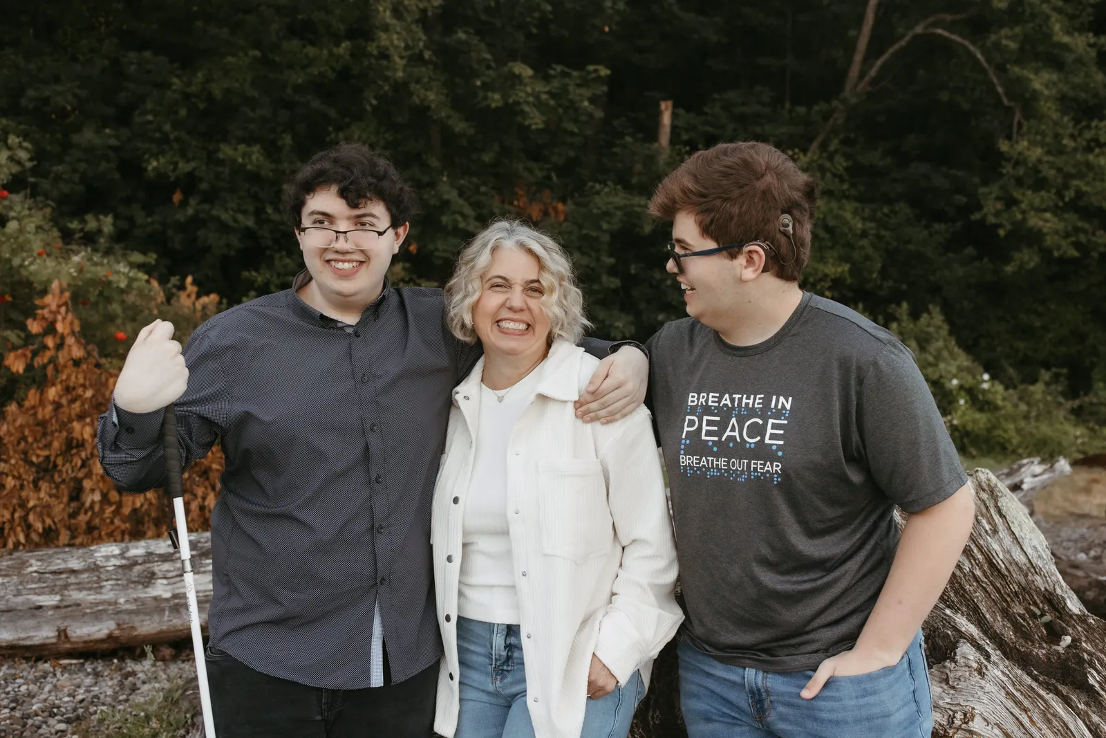 Three people are standing outside. One person has a cane.