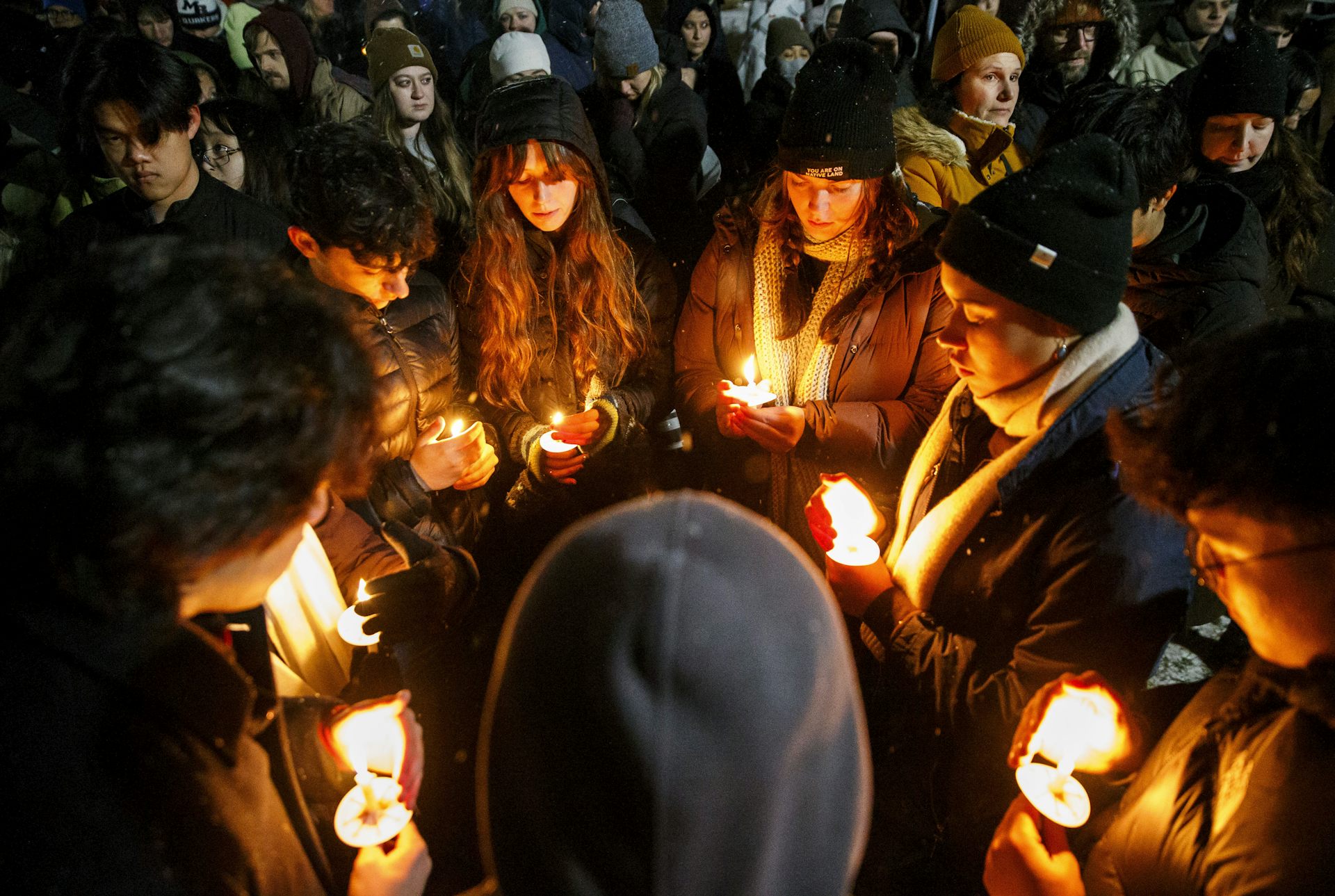 A group of people stand in a circle together and hold candles.