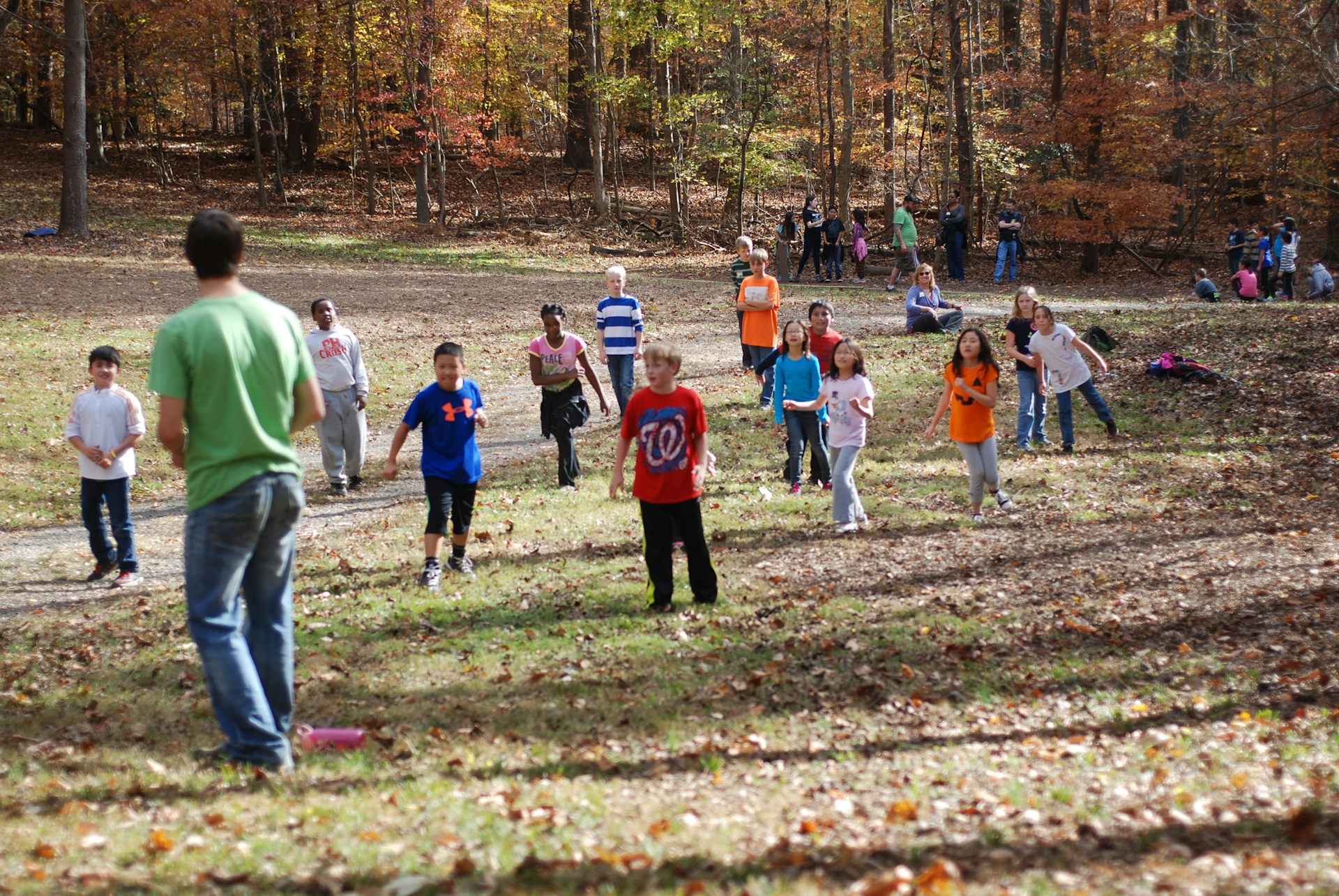 A group of young children play a game in a field on an autumn day.