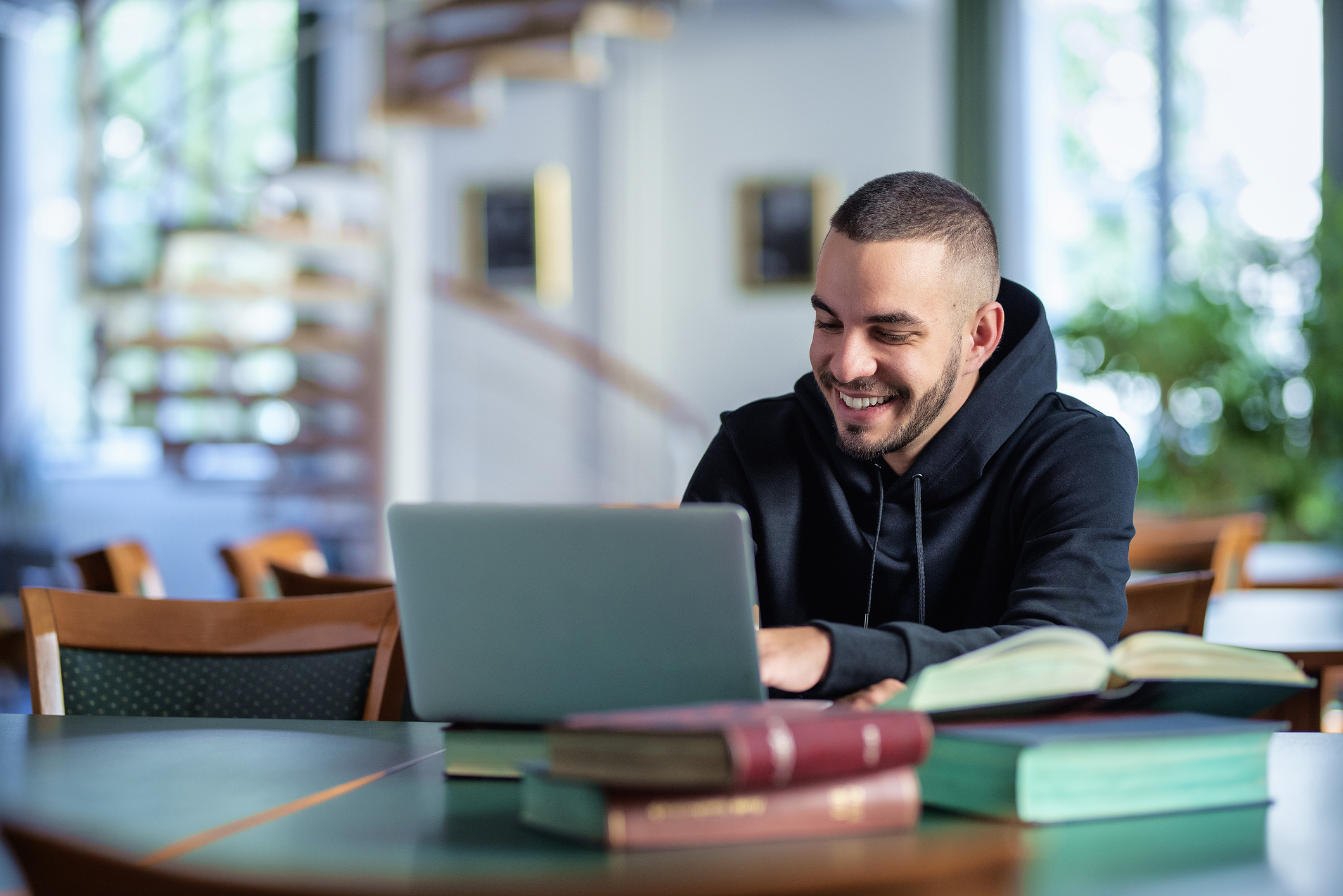 Male student using notebook and books and learning in the university library