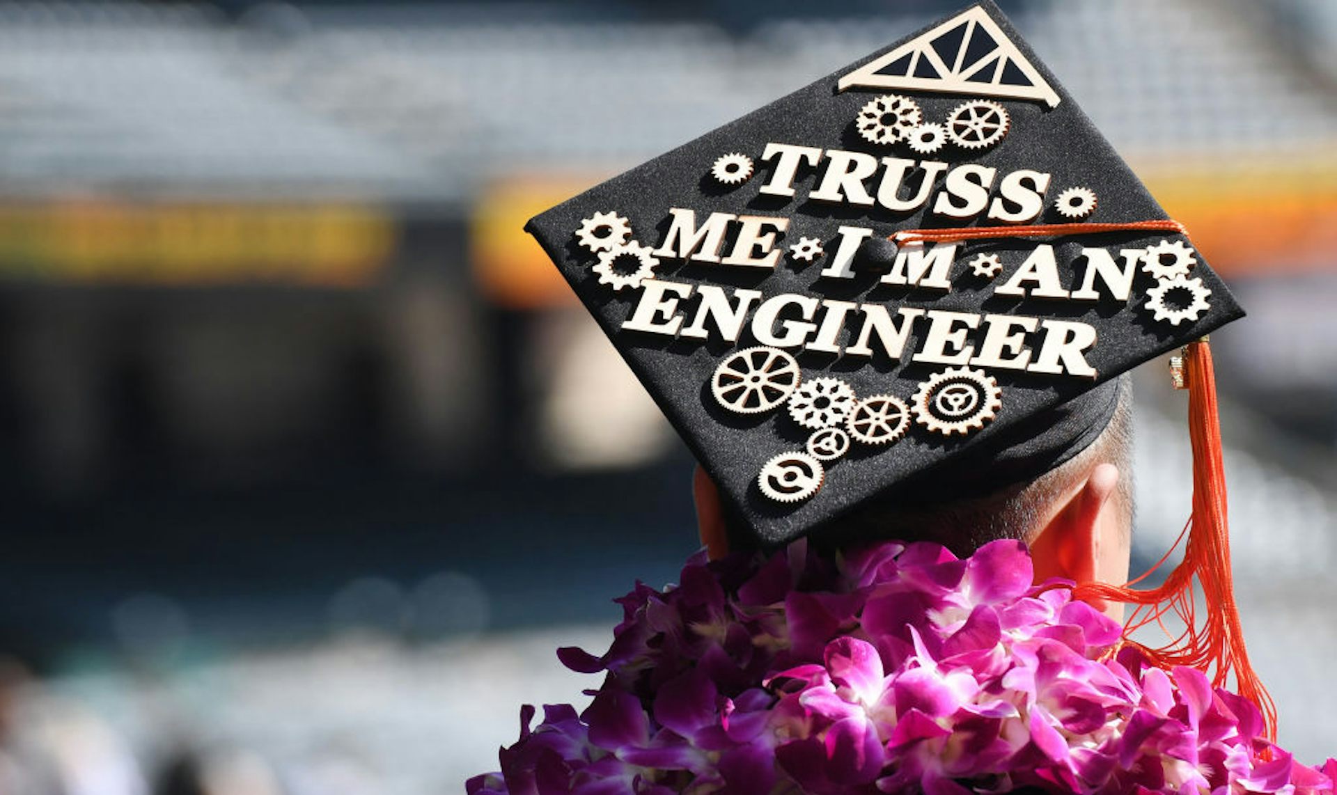 A graduate wearing a black cap decorated with the phrase 'Truss Me I'm an Engineer.'